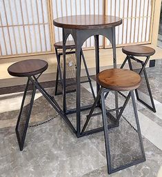 four stools and a table in front of a wall with japanese style screens on it