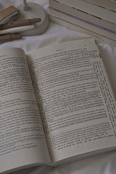 an open book sitting on top of a bed next to a pair of headphones