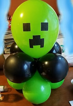 a green balloon sitting on top of a wooden table next to black and white balloons