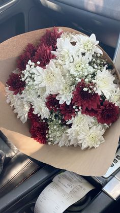 a bouquet of white and red flowers sitting on top of a car dashboard