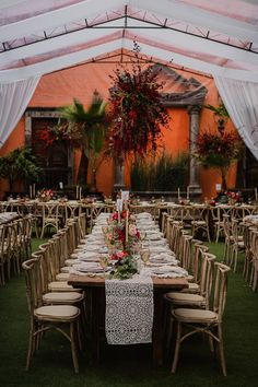 an outdoor tent with tables and chairs set up for a wedding reception in the grass