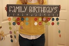 a woman holding up a sign that says family birthdays with beads hanging from it