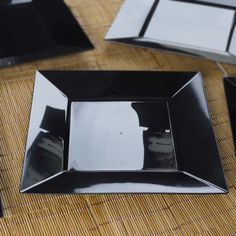 black and white plates are sitting on a bamboo tablecloth with silver trimmings