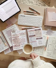 a person sitting at a table with notebooks and papers on top of the desk