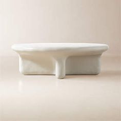 a white bowl sitting on top of a counter next to a wall with a light colored background