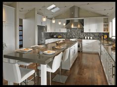 a large kitchen with white cabinets and wooden flooring, along with an island in the middle