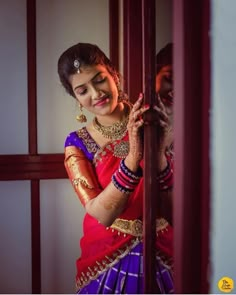 a woman in a red and purple sari is holding onto the door to her home