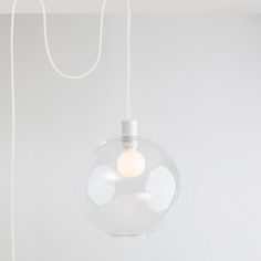 a clear glass light hanging from a ceiling fixture in a room with white walls and flooring