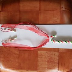 two candy canes tied to a white paper on top of a wooden table with a red ribbon