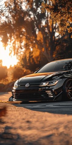 a black car is parked on the side of the road in front of some trees