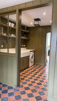 a kitchen with green cabinets and tile flooring next to a washer and dryer