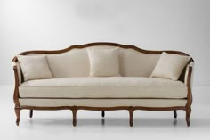 an old fashioned couch with four pillows on it's back and armrests