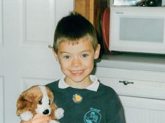 a young boy holding a stuffed dog in his hands