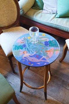 a small table with a glass on it in front of two chairs and a couch