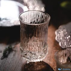 a glass sitting on top of a wooden table next to two pieces of silver foil