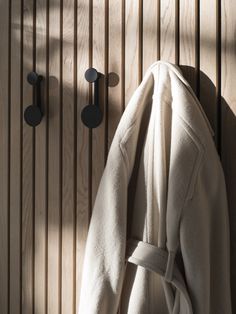 a coat is hanging on the wall next to two hooks that are attached to a wood paneled wall