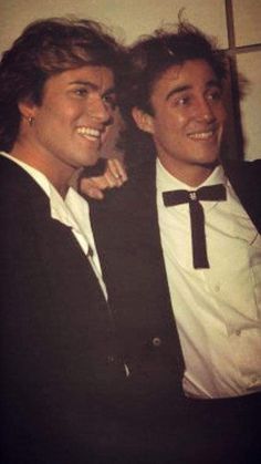 two young men in tuxedos posing for a photo with their arms around each other