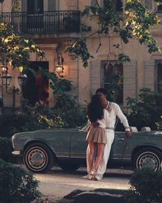 a man and woman kissing in front of a car