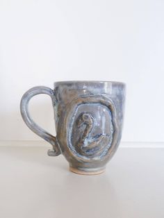 a ceramic cup with an image of a bird on it's side, sitting on a table