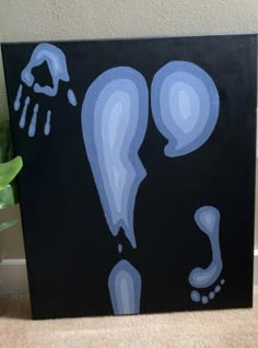 a painting with blue and white designs on black paper next to a potted plant