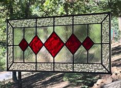 a stained glass window hanging from the side of a tree in front of some rocks