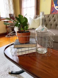 a glass bottle and some books on a coffee table with a plant in the middle