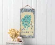 a blue and yellow poster hanging on a wall next to some seaweed in a vase