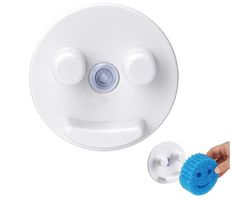 a hand holding a blue scrubber next to a white object with two eyes on it