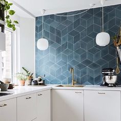 a kitchen with white cabinets and blue tiled backsplash, hanging lights above the sink