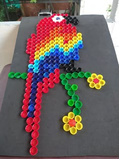 an art project made out of plastic cups with a rainbow colored bird on it's back