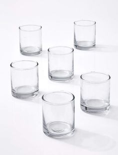 four clear glass tumblers sitting next to each other on a white surface with no one around them