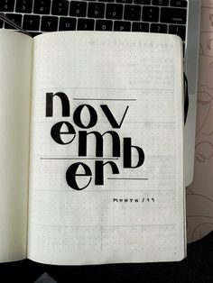 an open notebook with the words november written in black on it next to a keyboard