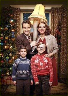 a family standing in front of a christmas tree with a lamp on it's head