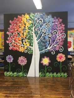 two colorful trees painted on black canvases in a classroom