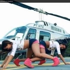 two women doing push ups in front of a helicopter