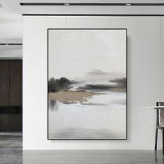 an abstract painting hangs on the wall next to a chair and table in a white room