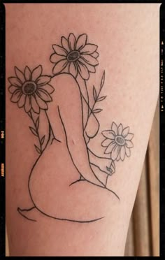 a woman with flowers on her thigh is sitting in front of the sunflowers