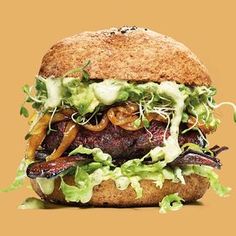 a burger with lettuce, tomato and onions on it is shown in front of an orange background