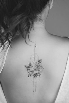 a woman's back with a rose tattoo on her left shoulder and an arrow in the middle