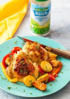 a blue plate topped with chicken and veggies next to a bottle of ranch seasoning