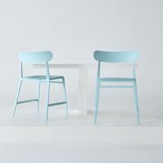 two chairs sitting next to each other near a white table with a blue chair on it