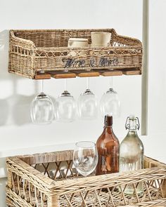 a wicker basket with wine glasses and bottles in it next to a wall mounted wine glass rack