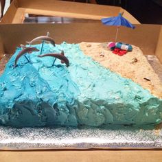 there is a cake in the box with dolphins on it and an umbrella above it