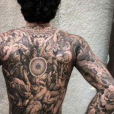 a man with tattoos on his back standing in front of a mirror