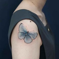 a small blue butterfly tattoo on the left upper half of the right arm and shoulder