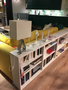 a living room filled with furniture and bookshelves next to a yellow couch on top of a hard wood floor