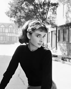 a black and white photo of a woman sitting on a bike with her hand on the handlebars