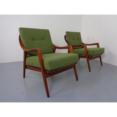 two green chairs sitting next to each other on a gray floor in front of a white wall