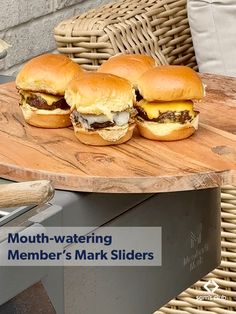 four hamburgers sitting on top of a wooden cutting board