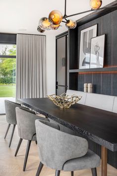 a dining room table with chairs and a vase on top of it in front of a large window